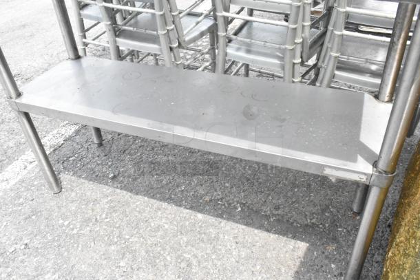 Stainless steel table with metal under shelf, durable frame, some surface wear, ideal for storage or display use.