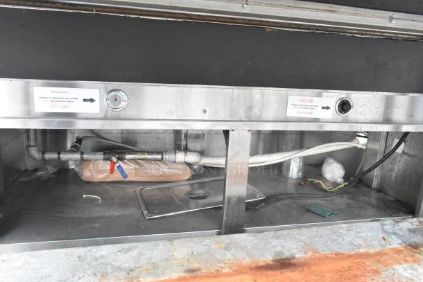 Metal commercial buffet station with sneeze guard. Features integrated pipes and gauges. Condition shows signs of use.