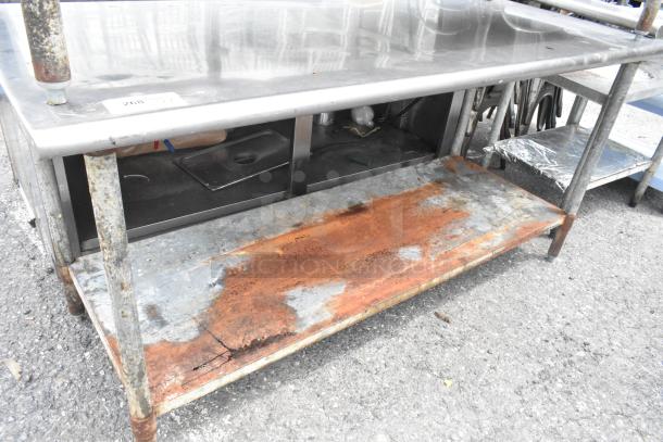 Stainless steel table with metal under shelf, visible rust on the shelf, dimensions 72x30x35 inches, includes an identification tag.