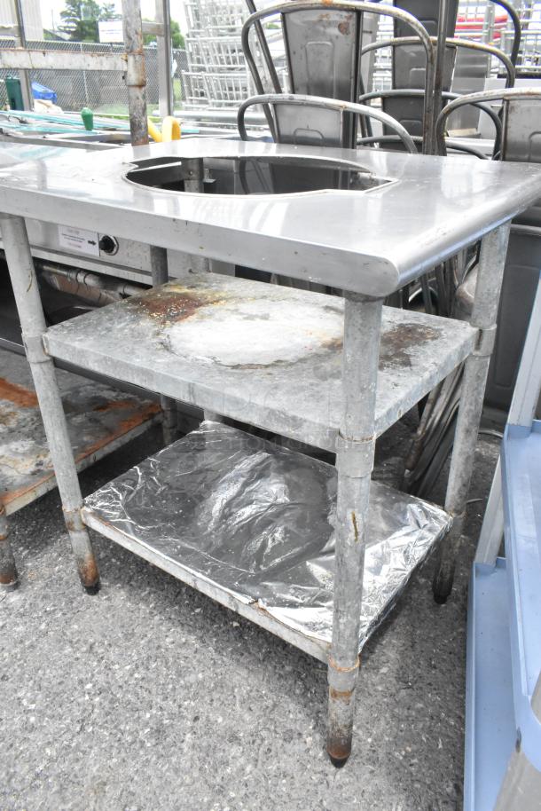 Stainless steel sauce table with cutout, featuring two metal under shelves. Some wear and surface rust visible.