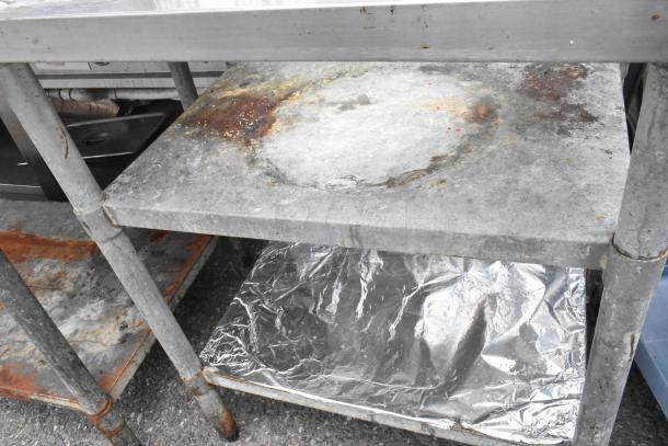 Stainless steel sauce table with cut out, featuring two metal under shelves. Visible wear and rust on surfaces.