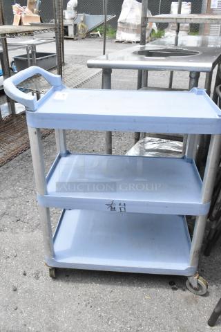 Blue poly 3-tier cart with commercial casters, sturdy metal handles, and minor surface markings. Ideal for industrial use.