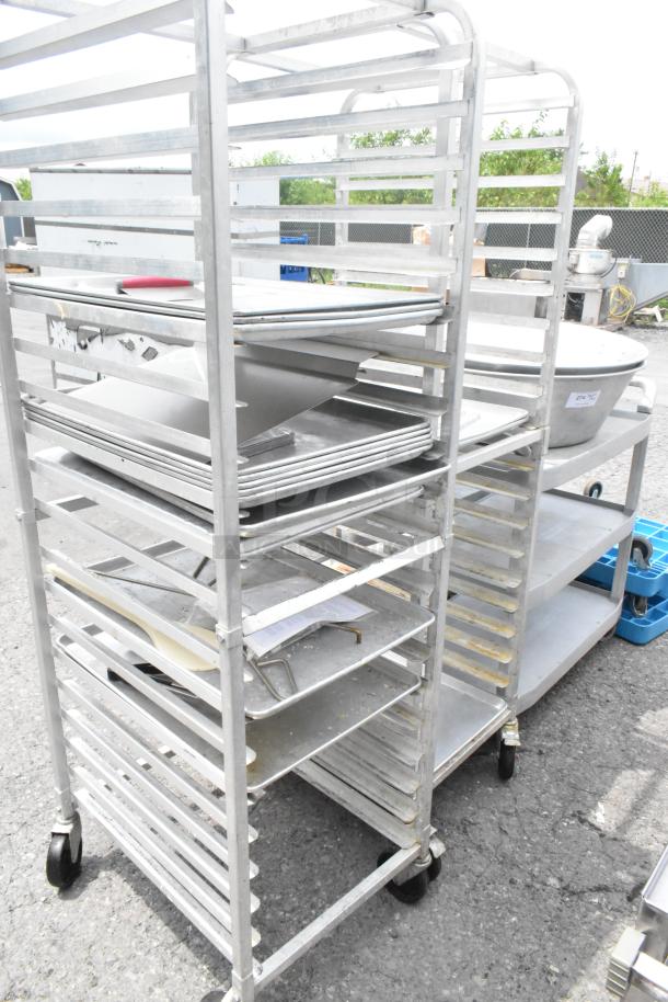 Two metal pan transport racks on commercial casters, used condition, multiple shelves, ideal for kitchen or bakery use.
