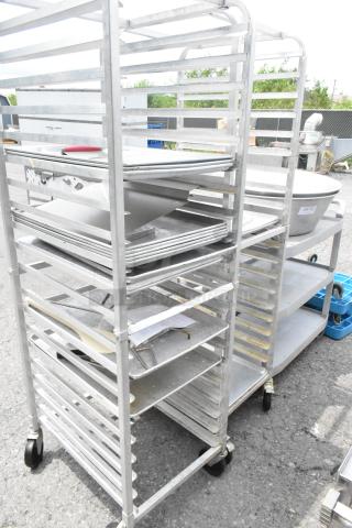 Two metal pan transport racks on commercial casters, used condition, multiple shelves, ideal for kitchen or bakery use.