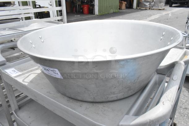 Large metal bowl, dimension 29x29x9 inches, displaying sturdy riveted construction. Appears well-used with visible scuffs.