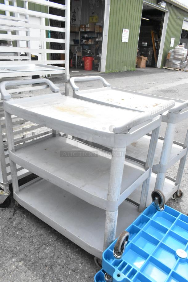 2 Tan Poly 3-tier carts with commercial casters, used condition, visible wear. Durable and mobile, ideal for industrial use.