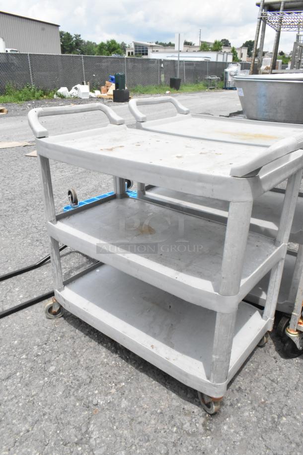Tan poly 3-tier cart on commercial casters, industrial design, used condition, sturdy handles, outdoor setting.