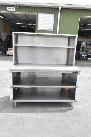 Stainless steel table with over shelf and two under shelves, durable design, used condition, ideal for storage and workspace.