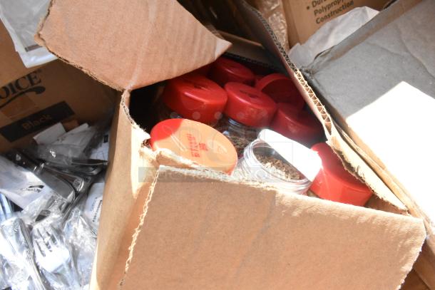 _Box of new scratch and dent items, including seasoning jars with red lids, dish caddy, and sandwich wraps._