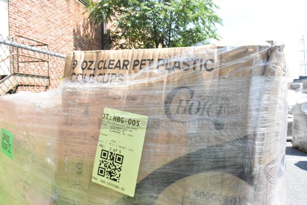 Plastic-wrapped pallet of auction items, including cartons labeled "9 oz. Clear PET Plastic Cold Cups." Includes a lot tag with QR code.