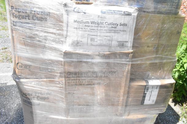 Pallet with boxed items including yogurt cups, cutlery sets, and containers. Wrapped in plastic, showing brand labels.