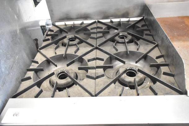 Vulcan stainless steel commercial gas range with 4 burners, griddle, convection oven, and overshelf. Slight wear visible.