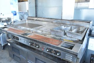 Stainless steel commercial countertop flat top griddle with multiple control knobs, showing signs of wear and grease trays.