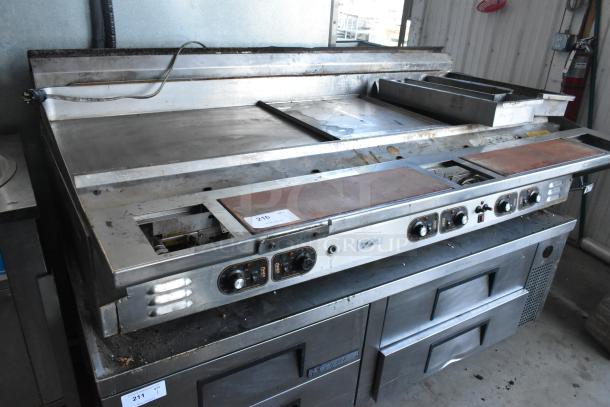 Stainless steel commercial countertop flat top griddle with control knobs, visible wear, and storage drawers below. Item tag "210".