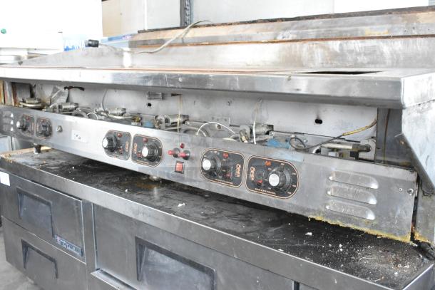 Stainless steel commercial countertop flat top griddle with control knobs, showing signs of use and wear.