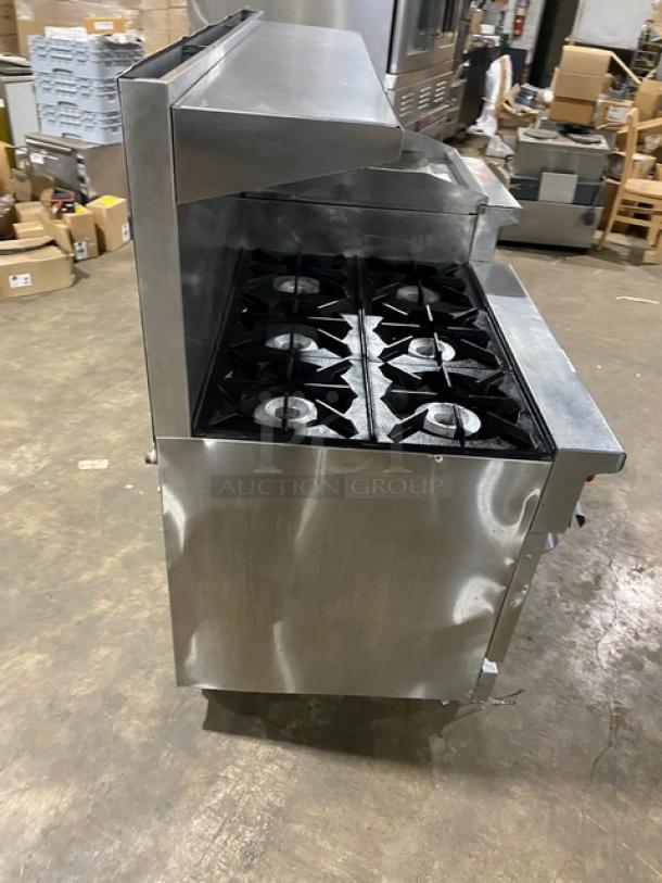 Therma-Tek commercial stainless steel 6-burner range with raised flat griddle, double oven, broiler, and salamander shelf on casters.