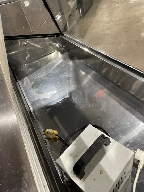 Commercial black slanted glass refrigerated bakery/deli display case with rear prep area, sliding doors, and lower storage.
