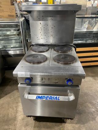 Imperial stainless steel 4-burner electric range/oven combo with backsplash, overhead salamander shelf, and wire oven rack. On legs.