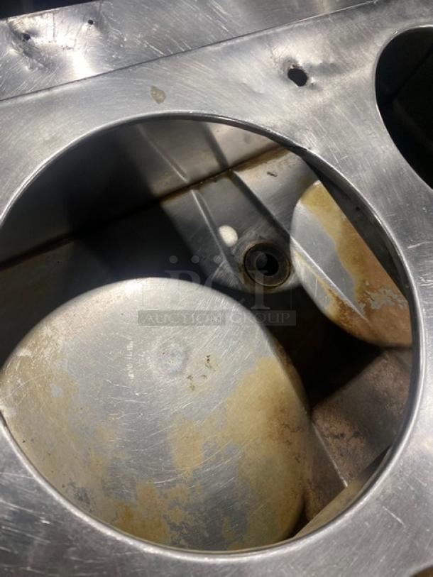 Commercial stainless steel cabinet with double shelf base, drop-in adapter plate, and drain hole. Visible surface wear.