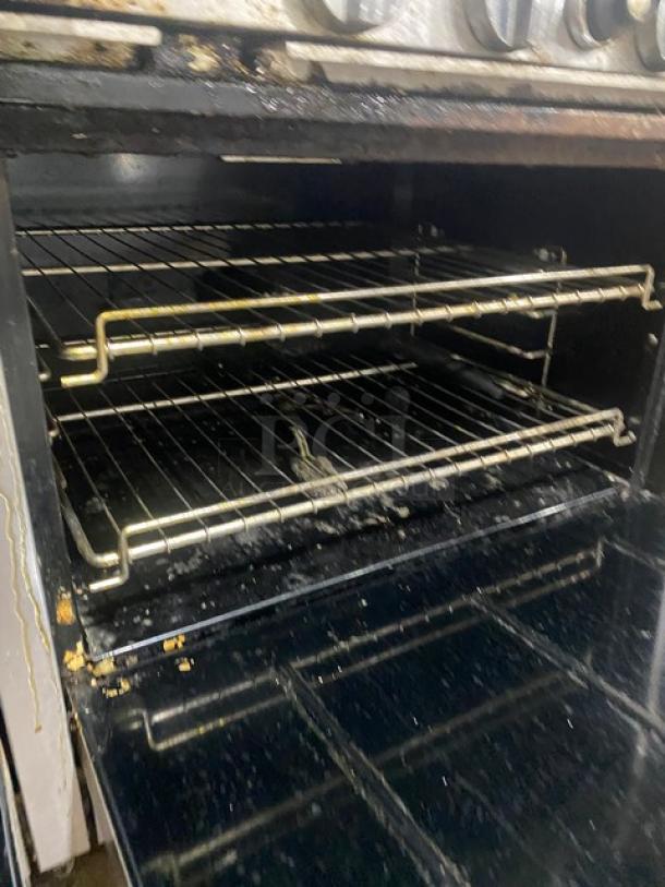 Bakers Pride stainless steel range double oven interior with wired racks, showing signs of use. Model 60BP10BS26N.