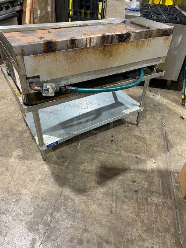 L&J gas-powered flat griddle with undershelf stand, stainless steel, Model JRMG48NG, with back/side splash, gas hose, on legs.