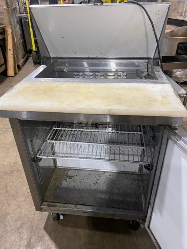 Avantco stainless steel refrigerated single door prep table with cutting board, poly-coated wire rack, casters; 115V. Signs of use.