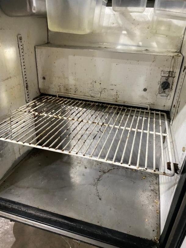 True TSSU-27-08 refrigerated prep table interior, featuring a poly-coated wire rack. Used condition, visible wear.
