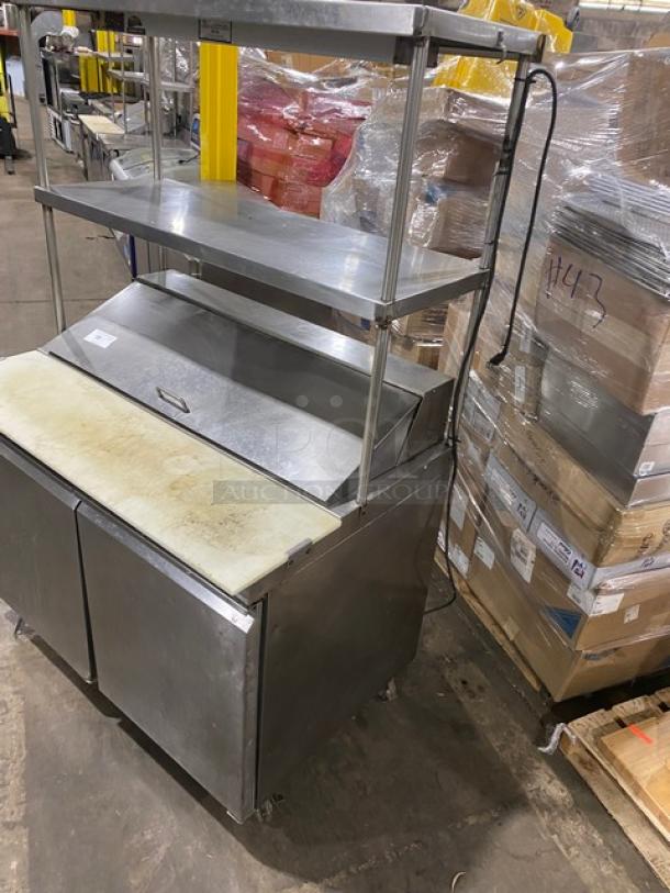 Commercial stainless steel 2-door refrigerated Bain Marie prep table with double overhead shelf and Hatco strip warmer on casters.