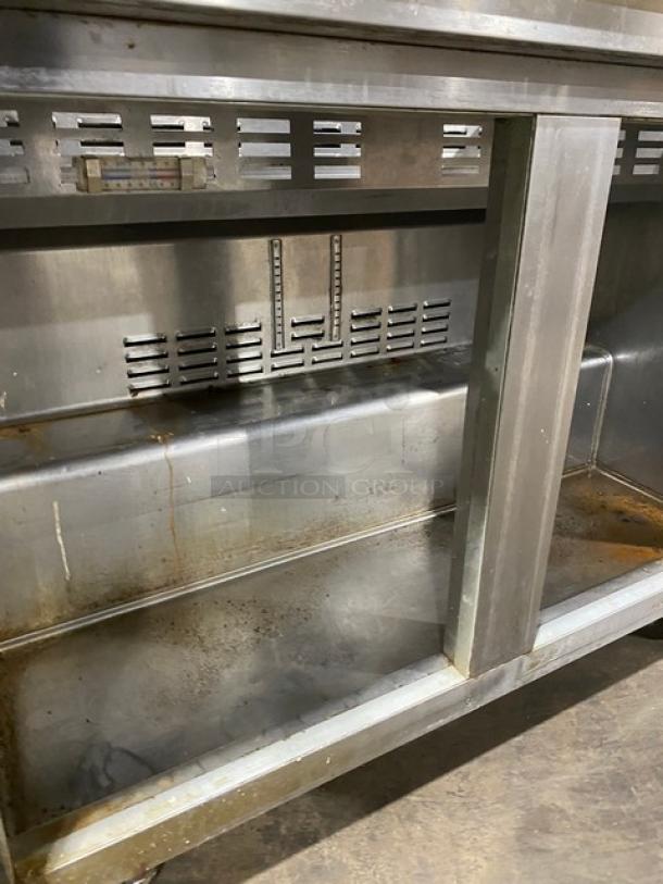 Commercial stainless steel prep table with 2 doors, refrigerated Bain Marie style, double overhead shelf, Hatco strip warmer, and casters. Visible wear.