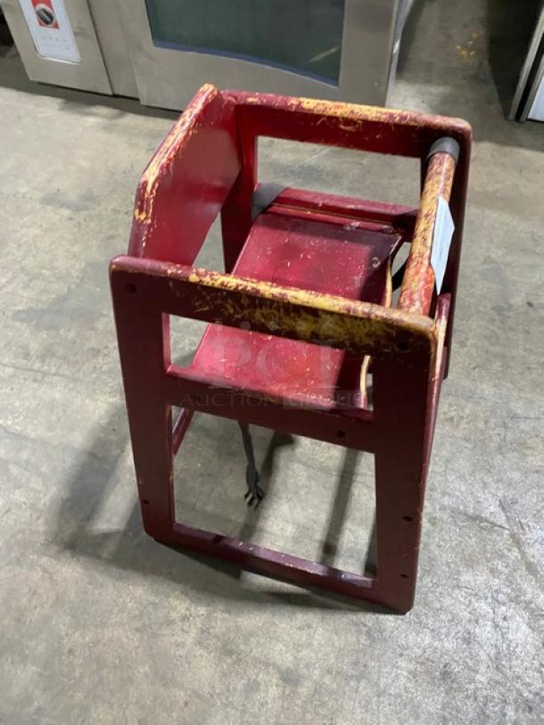 Lot of stackable commercial wooden highchairs with safety buckles. Shows visible wear. Ideal for restaurants.