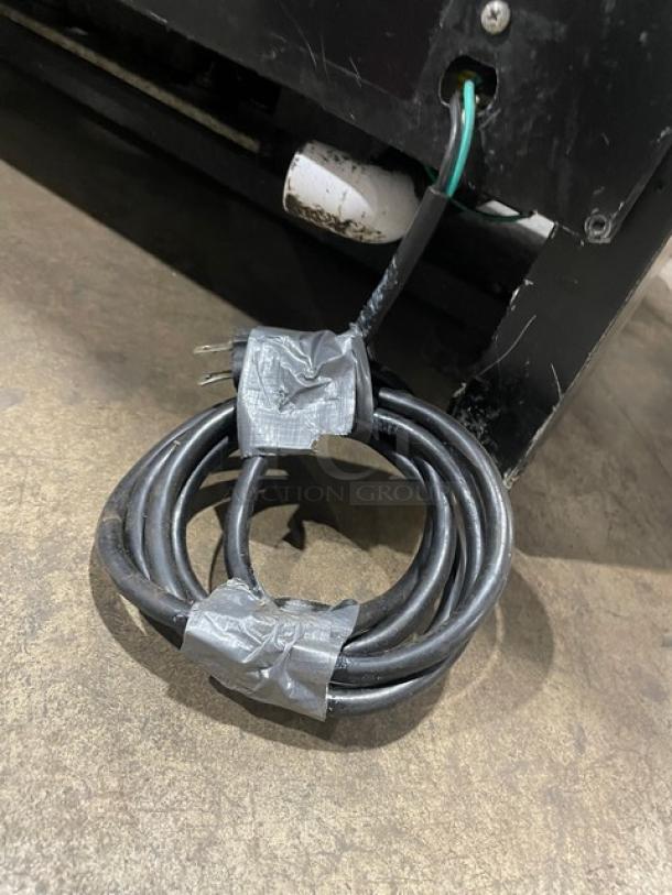 Black power cord attached to a Tor-Rey refrigerated deli merchandiser, wrapped with duct tape. Model: TEM150NLUL.