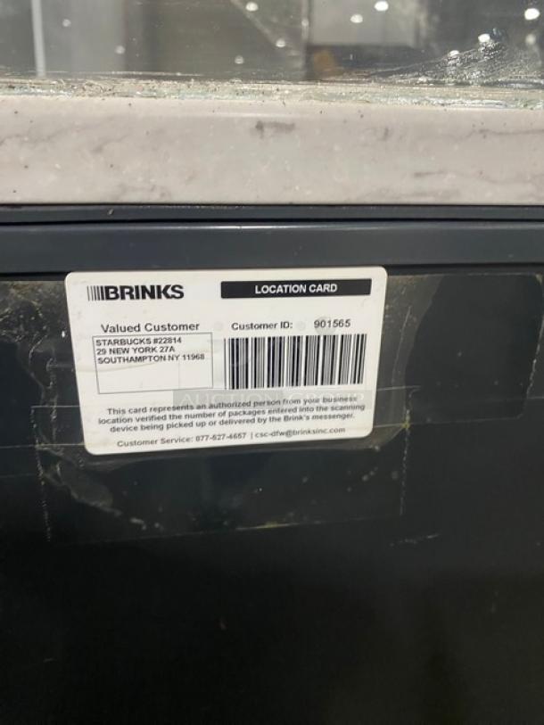 Black multi-level refrigerated display case with glass showcase and legs. Includes Brinks location card marked for Starbucks.