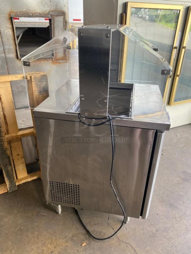 Turbo Air M3 Series refrigerated prep table MST28N711S with clear overhead sneeze guard, poly-coated wire rack, on legs.