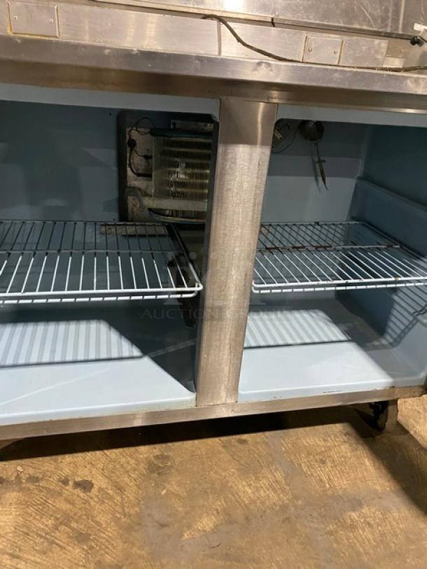 Commercial stainless steel two-door worktop table with backsplash, poly-coated wire racks, and casters. Good condition.