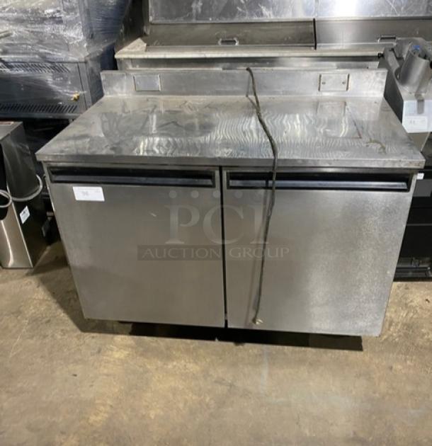 Commercial stainless steel 2-door worktop table with backsplash, poly-coated wire racks, and casters; gently used.