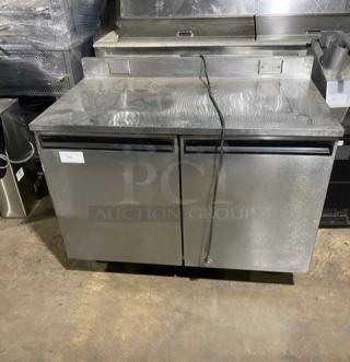Commercial stainless steel 2-door worktop table with backsplash, poly-coated wire racks, and casters; gently used.