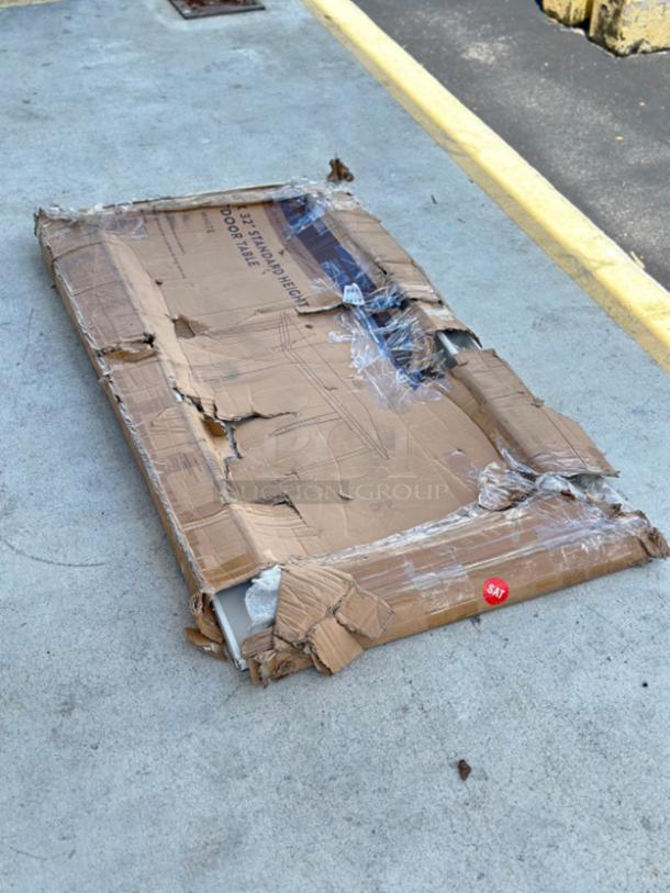 Damaged box containing a new Lancaster Table & Seating Alloy 63" x 32" pearl white outdoor table, model 164RD326WHT.