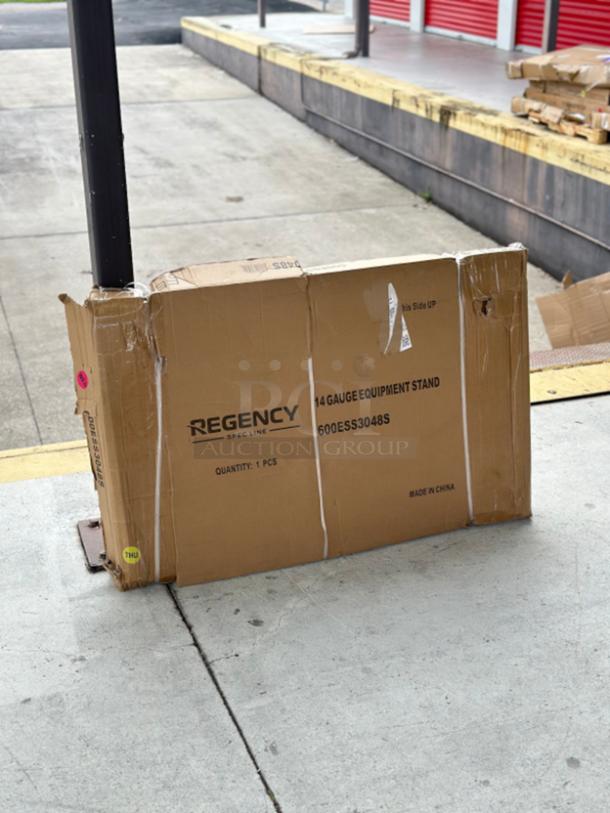 Brown box containing Regency Spec Line 14-gauge stainless steel equipment stand model 600ESS3048S, box shows wear.