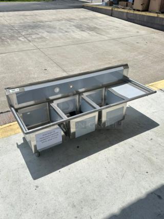 Brand new Regency 72.5" stainless steel three-compartment sink with right drainboard, 16-gauge, minor dents visible.
