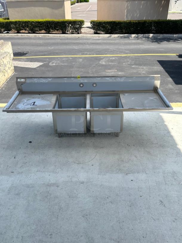Regency 86" 16-gauge stainless steel two-compartment sink, 24"x24"x14" bowls, dual drainboards, scratch, and dent condition.