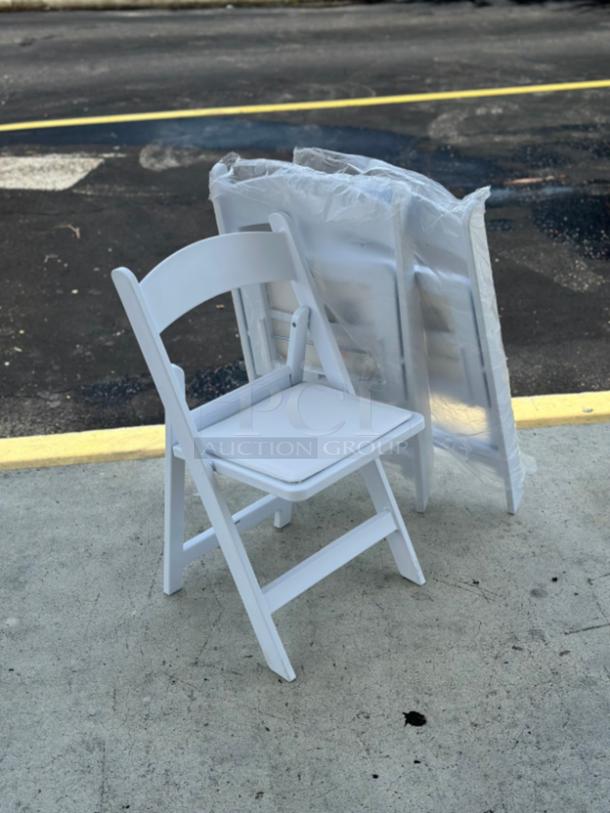 Lancaster Table & Seating white resin folding chair with vinyl seat, model 427FCRVINWHT, shown on concrete. New condition.