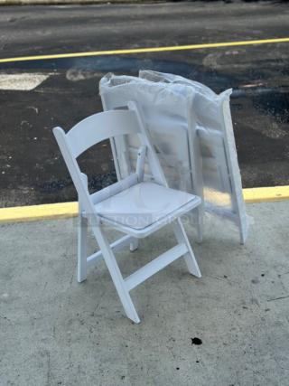 Lancaster Table & Seating white resin folding chair with vinyl seat, model 427FCRVINWHT, shown on concrete. New condition.