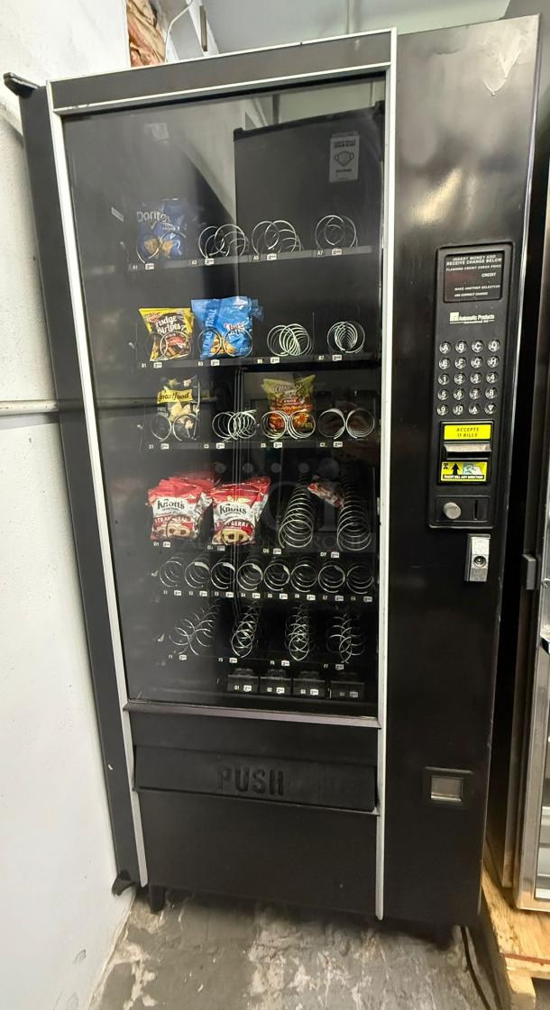 AUTOMATIC PRODUCTS LCM I vending machine, multiple snack rows, keypad, coin slot, used condition.