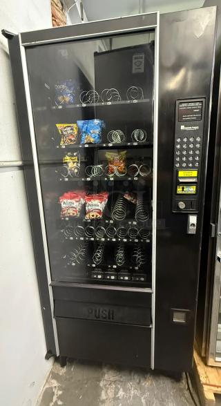AUTOMATIC PRODUCTS LCM I vending machine, multiple snack rows, keypad, coin slot, used condition.