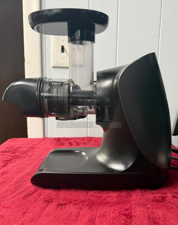Ninja Cold Press Juicer Pro, 150W, graphite color, total pulp control, excellent condition, side view on red surface.