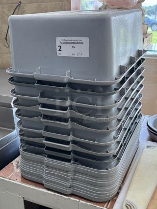 Stack of 9 gray bus pans, with auction label tagged "2." Sturdy plastic, used, showing minor wear, ideal for kitchen use.