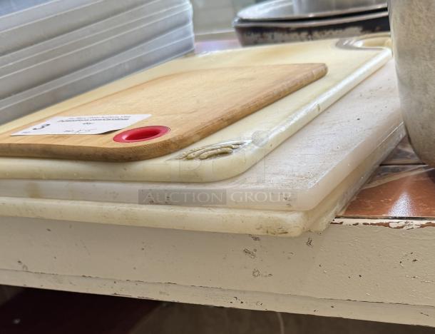 Five assorted cutting boards with visible wear, including wood and plastic materials. One board has red grip handle.