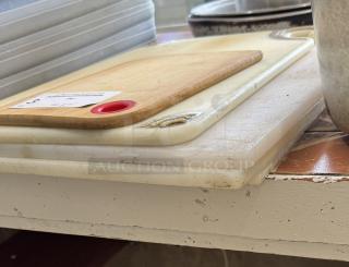 Five assorted cutting boards with visible wear, including wood and plastic materials. One board has red grip handle.