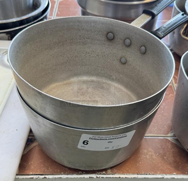 Two metal sauce pans with riveted handles, visibly worn, auction label showing "6" and "2 x bid."