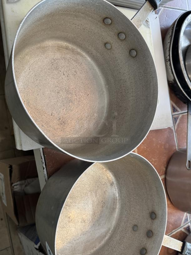Two metal sauce pans with handles, showing visible wear. Suitable for auction, ideal for kitchen use.